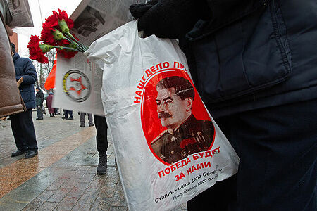 21.12.2022, Москва. Гвоздики и пакет с портеретом Сталина в руках мужчина.
