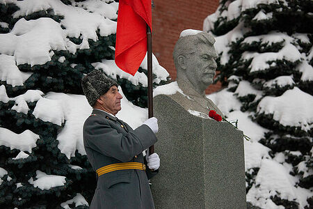 21.12.2022, Москва. Старший офицер в отставке стоит с флагом у памятника Сталину в День его рождения.