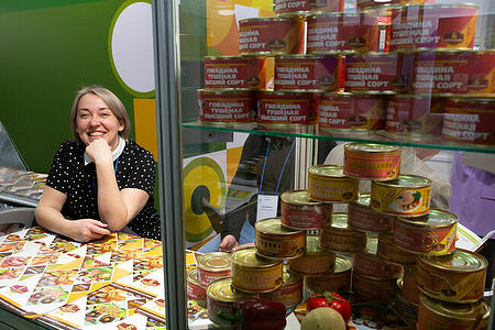 07.02.2023, Москва. Весёлаяя женщина на стенде с мясными консервами на выставке «Продэкспо» 2023.
