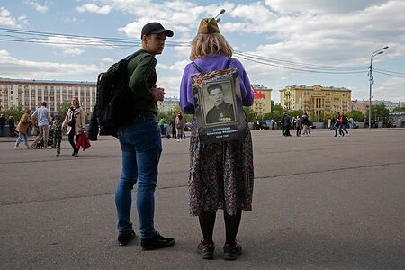 09.05.2023, Москва, Парк Горького, День Победы. Женщина в пилотке с прикреплённым к рюкзаку на спине портретом родственника, воевавшего во время Великой Отечественной Войны.