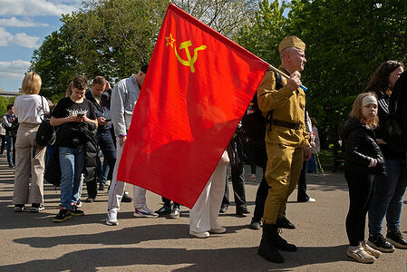 09.05.2023, Москва, Парк Горького, День Победы. Мужчина в военной форме и с красным флагом стоит в очереди за гречневой кашей, приготовленной в полевой кухне.