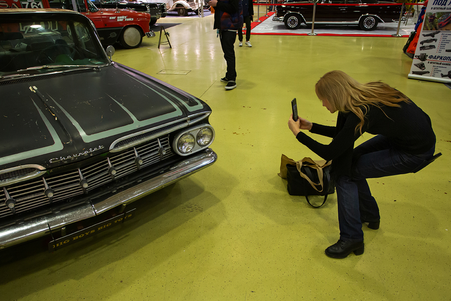 02.12.2022, Москва, Выставка, посвященная путешествиям и технике. «Поехали 2022» в Экспоцентре. Женщина фотографирует автомобиль Chevrolet.