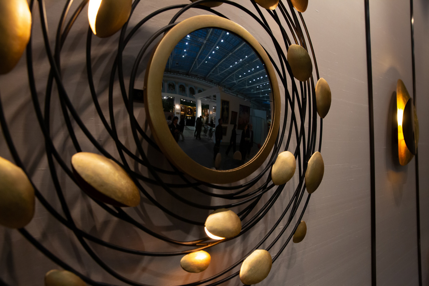 23.11.2022, Москва. 48-й Российский Антикварный Салон & Lifestyle "Искусство интерьера». Отражение интерьера Салона в одном из экспонатов, висящих на стене.