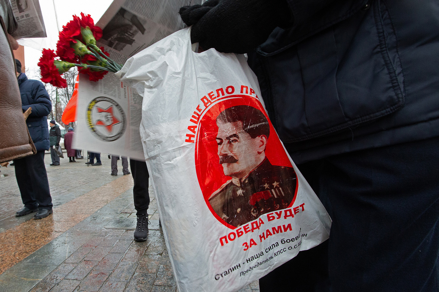 21.12.2022, Москва. Гвоздики и пакет с портеретом Сталина в руках мужчина.