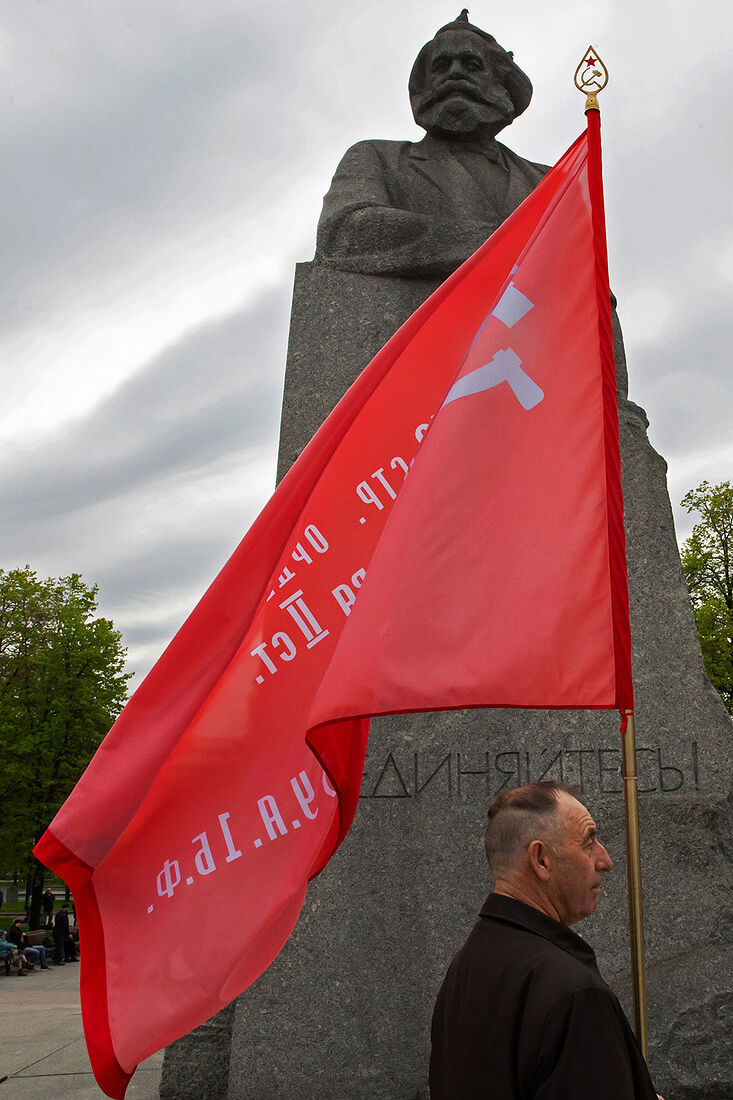 01.05.2023, Москва. Встреча депутатов фракции КПРФ с избирателями в формате патриотического митинга возле памятника Карлу Марксу. Мужчина с флагом у памятника Карлу Марксу.