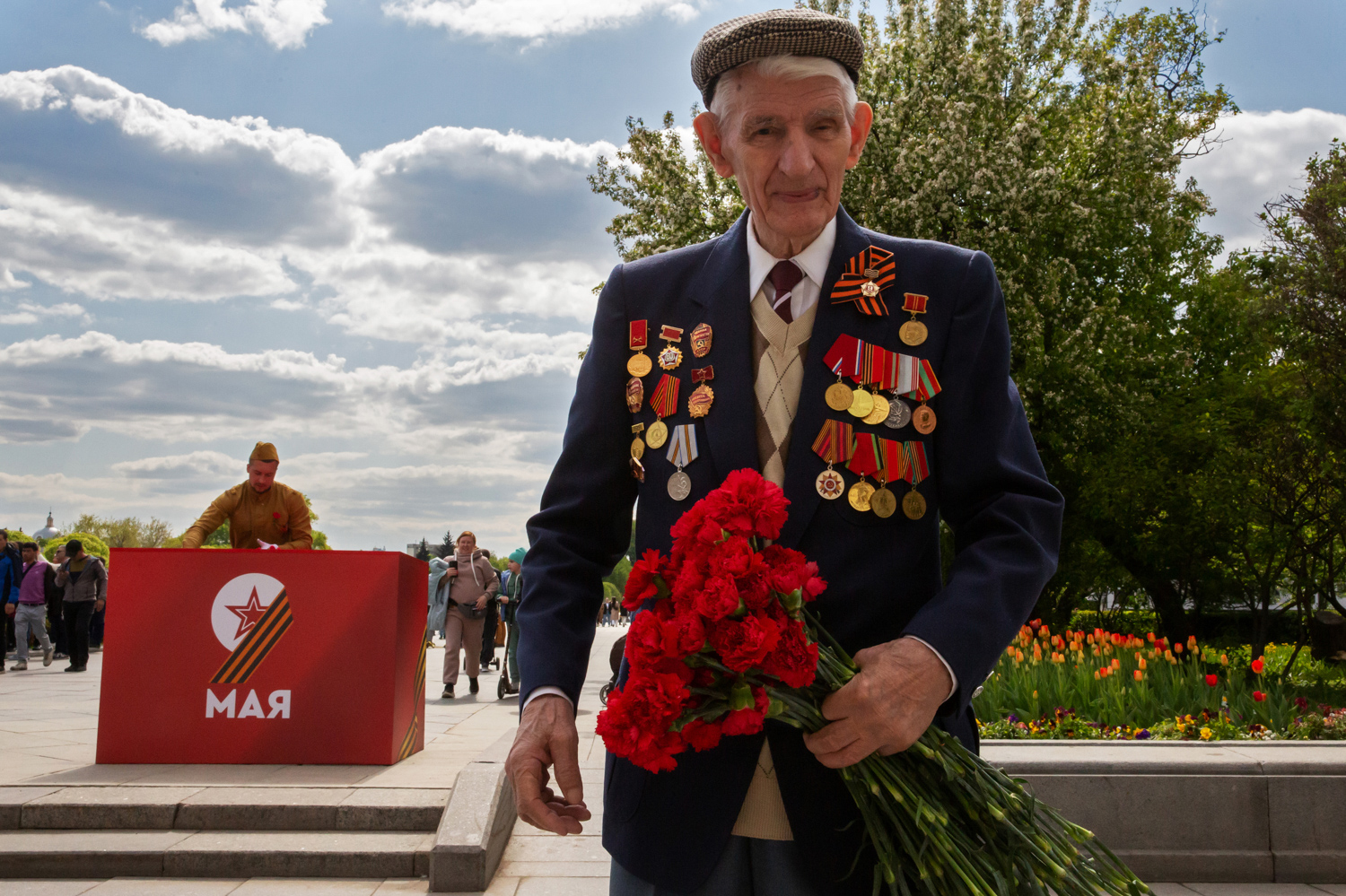 09.05.2023, Москва, Парк Горького, День Победы. Пожилой мужчина с медалями на пиджаке и букетом гвоздик в руке в День Победы.